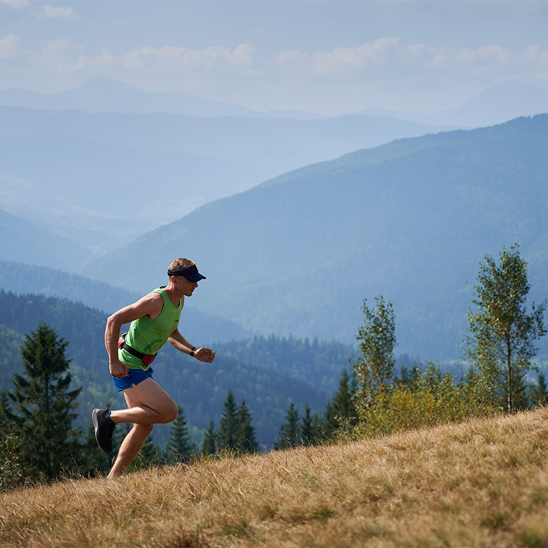 Athletic young man running up hill mountains