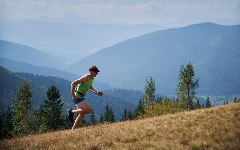 Athletic young man running up hill mountains